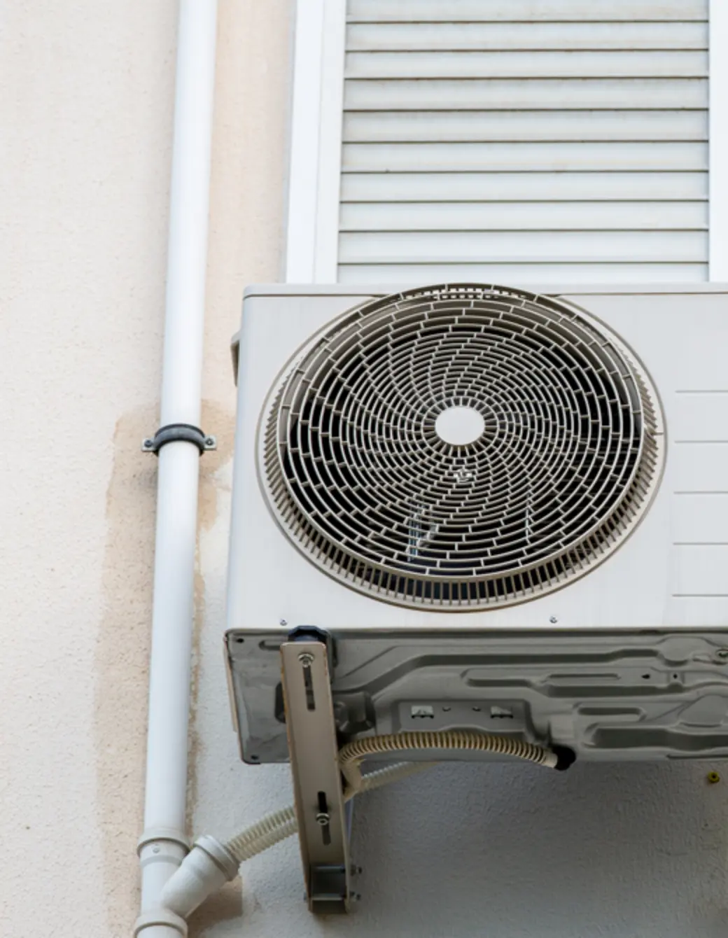 Outdoor air conditioning unit mounted on a wall serviced by Umpqua Sheet Metal in Roseburg, OR