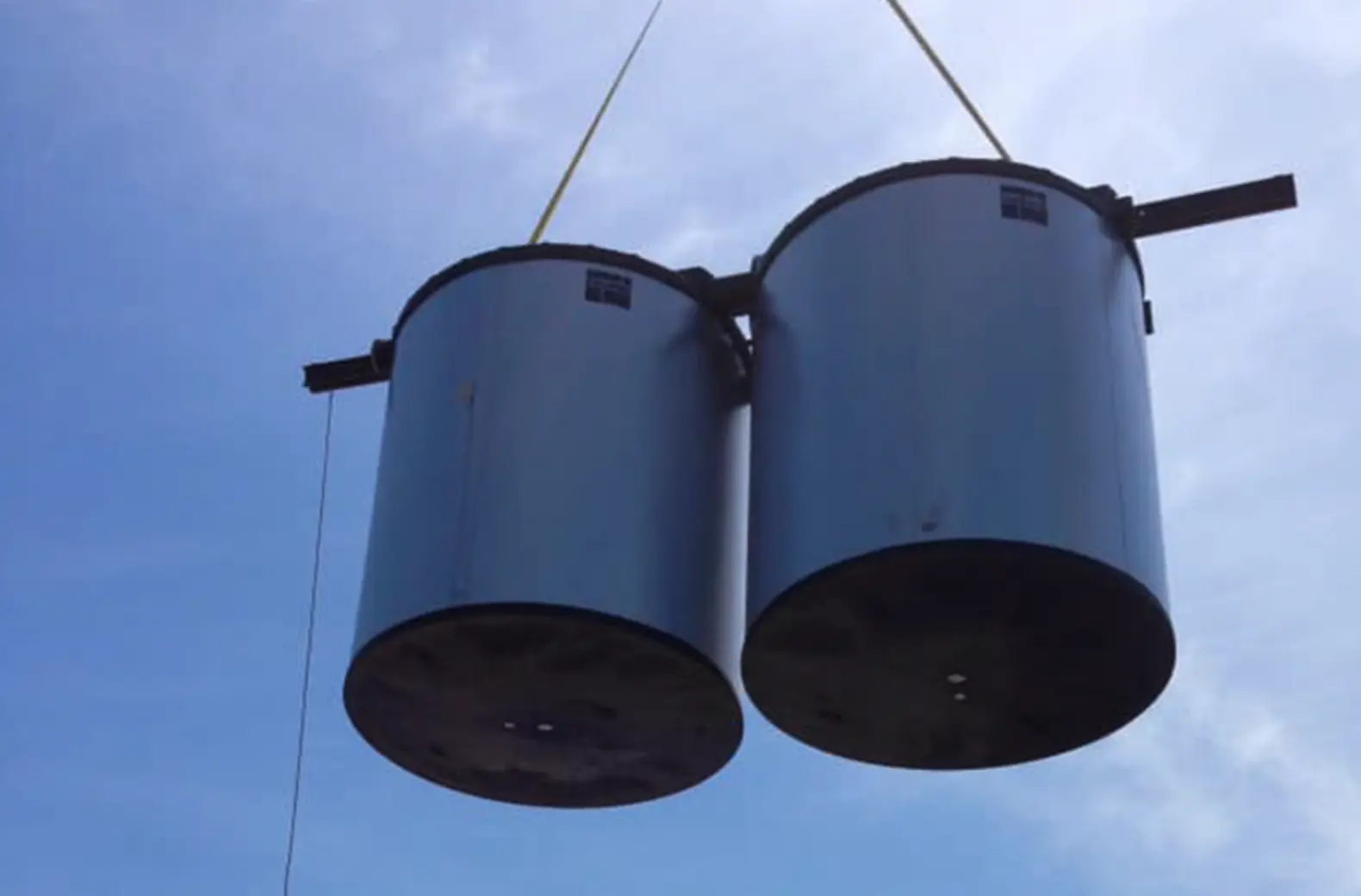 Umpqua Sheet Metal industrial crane lifting heavy metal tanks on a job site in Southern Oregon