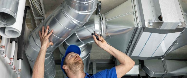 HVAC technician performing overhead system repair and inspection in Southern Oregon