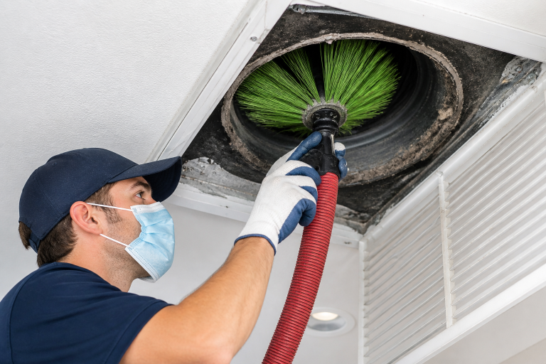 HVAC technician cleaning air ducts with rotary brush to remove dust and improve indoor air quality and airflow